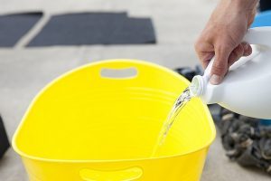 Immagine di mano che versa candeggina nel secchio senza toccarla