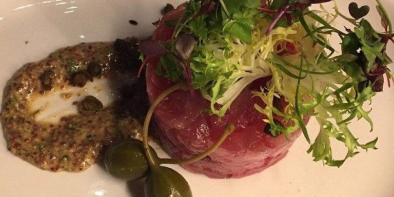Tartare di tonno crudo alla greca con salsa di olive decorato con insalata