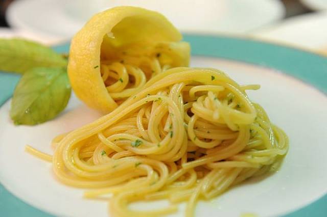 Pastasciutta alla salsa di limone Spaghetti al limone serviti con basilico e buccia del frutto per decorazione