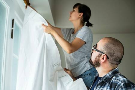 Uomo e donna montano una tenda ancora umida sul bastone