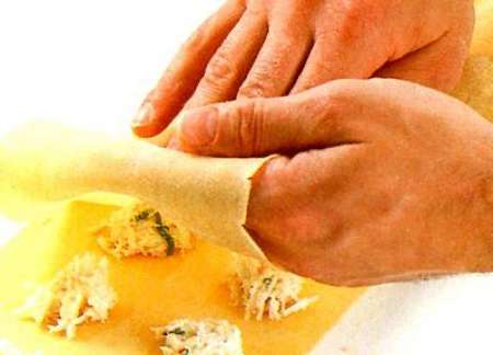 Fotografia di mani che ripiegano la sfoglia sul ripieno dei ravioli