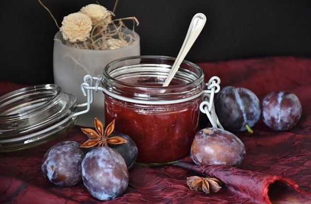 Fotografia di salsa di prugne secche in contenitore e prugne fresche