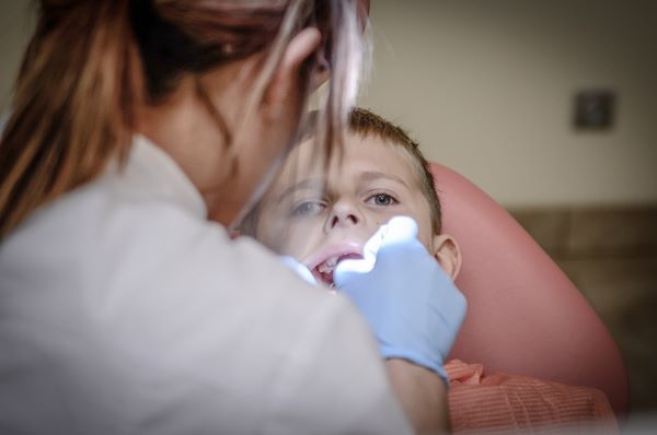 Assistente odontoiatrica esamina la bocca di un bambino