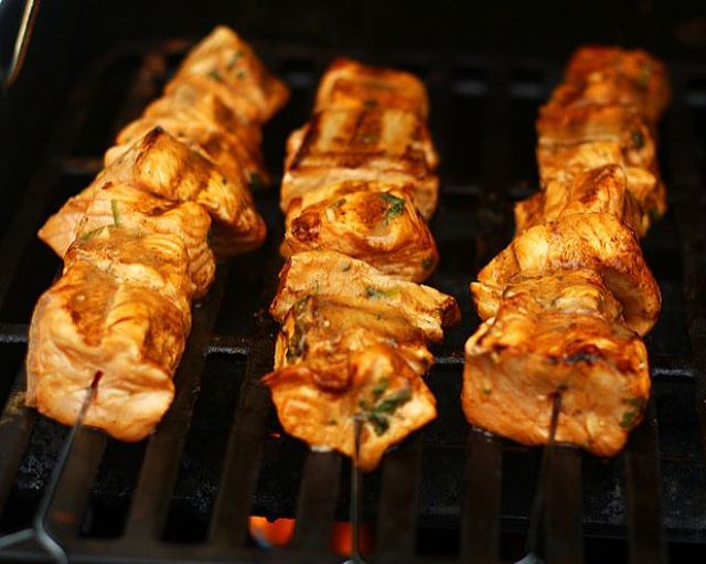 Spiedini di salmone marinati e cucinati in agrodolce alla giapponese Cottura degli spiedini di salmone dopo riposo nella marinata agrodolce giapponese
