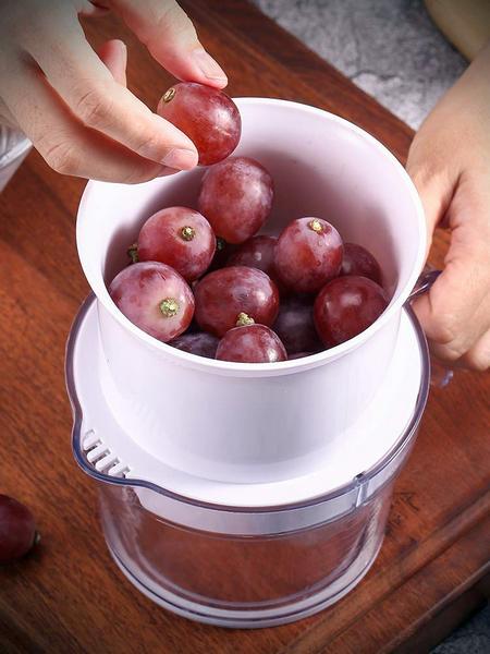 Acini d'uva messi nel pratico estrattore manuale per poi estrarne il succo facilmente