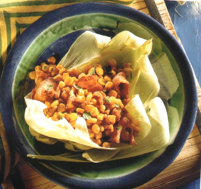 Insalata di mais, salsiccia e pancetta nel piatto su foglie del cereale