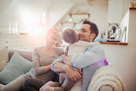 Genitori e figllia sorridenti sul divano