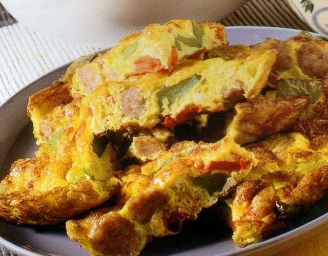 Pezzi di tortilla contadina con peperoni e salsiccia allo zafferano nel piatto