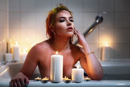 Donna s'immerge nell'acqua calda del bagno dopo aver acceso candele rilassanti
