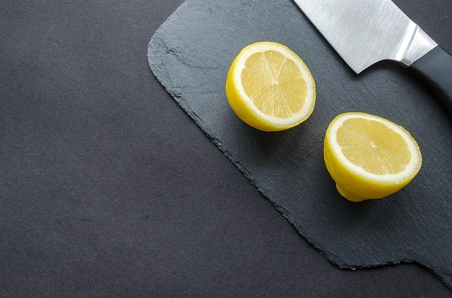 Limone tagliato a metà con il coltello sul tagliere