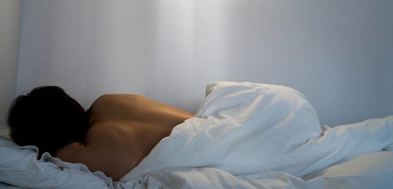 Persona dorme nuda tra le lenzuola