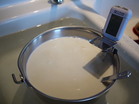 Latte caldo nel pentolino fatto raffreddare in acqua fredda