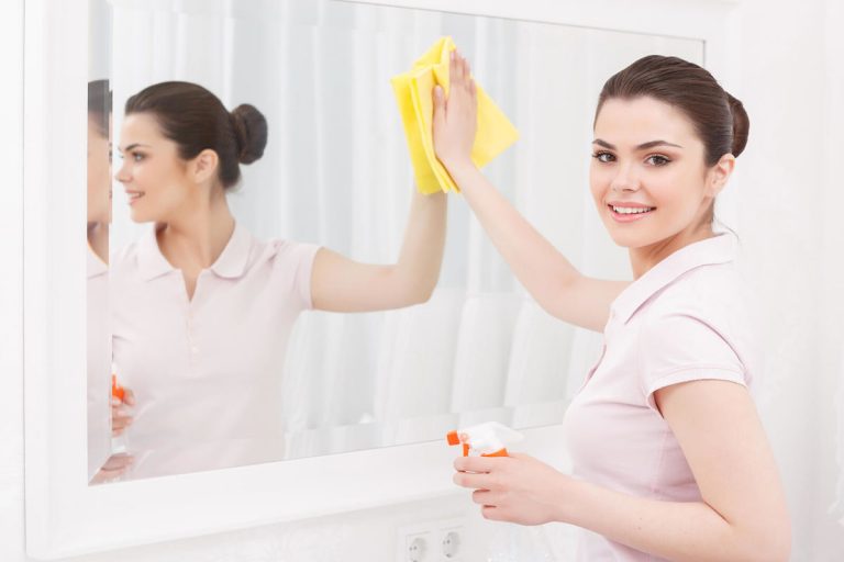 Donna pulisce specchio con pstrofinaccio svedese e detergente naturale