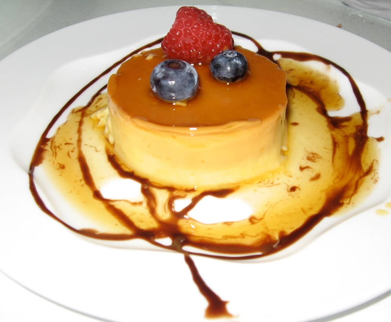 Aspetto del crème caramel alla cannella senza panna decorato con fragola e mirtilli