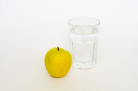Bicchiere dìacqua con mela accanto