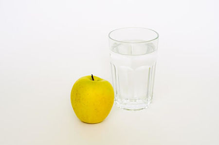 Bicchiere dìacqua con mela accanto