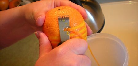 Donna preleva la parte commestibile della scorza dellìarancia con un rigalimoni