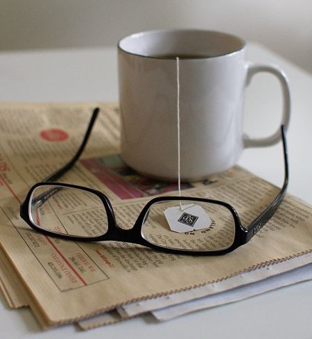 Tazza contenente infuso biologico con accanto paio di occhiali sulla scrivania