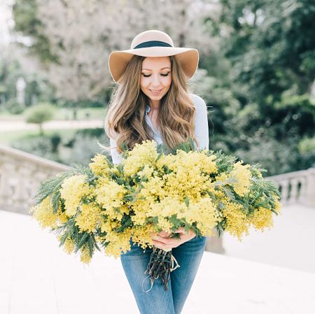 Donna tiene un mazzo di mimosa tra le mani