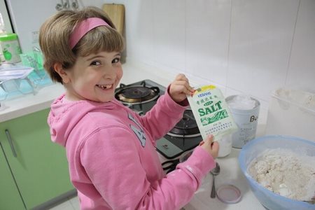 Bambina sorridente davanti agli ingredienti della pasta di sale
