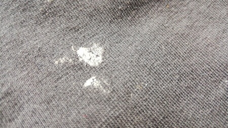 Macchia di cera bianca di candela su tessuto grigio