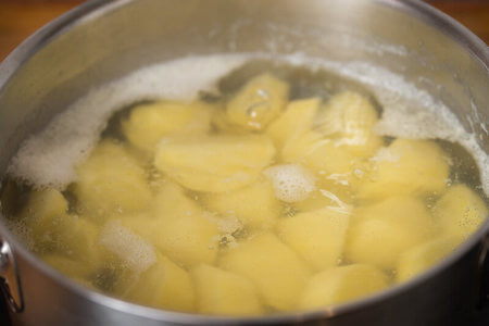 Patate sbucciate e tagliate a tocchetti bollono nella pentola
