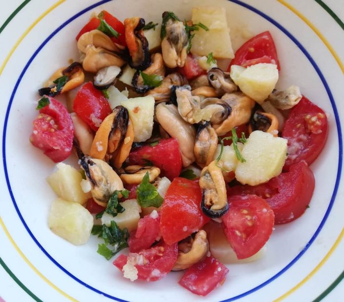 Insalata di cozze, patate e pomodorini nel piatto di portata