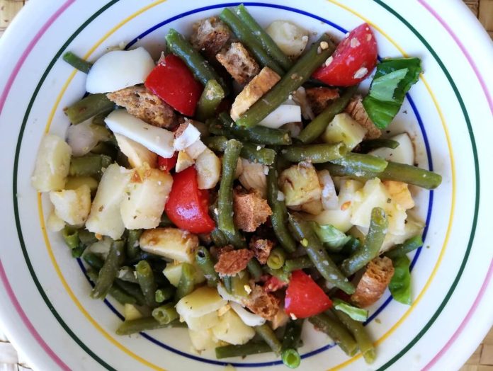 Ciotola contenente insalata di fagiolini, patate, pomodorini e uova sode con frisella spezzettata