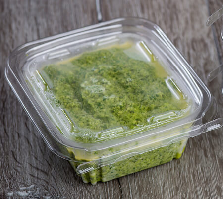 Pesto di zucchine coperto di olio in vaschetta per alimenti