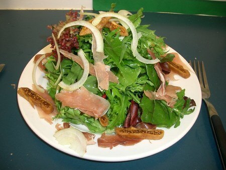 Piatto con dentro insalata con fichi reidratati e prosciutto crudo