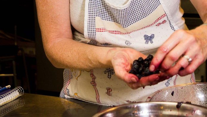 Donna con mani macchiate di uva nera