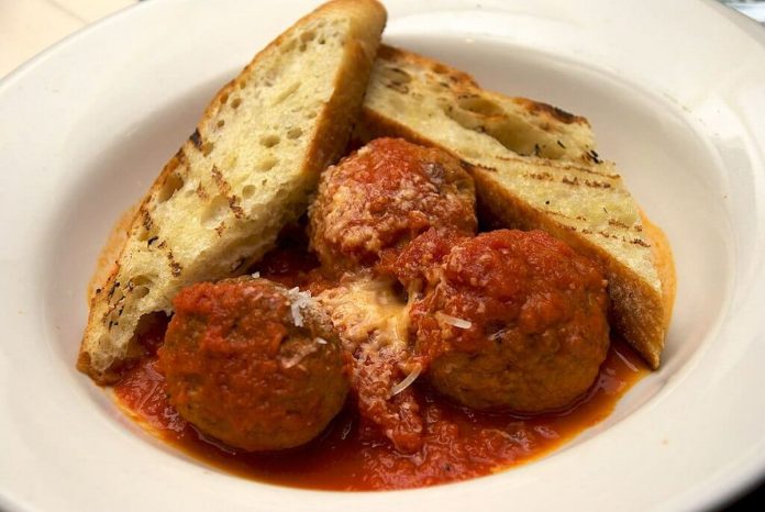 Piatto contenente polpette a sugo non fritte e pane casereccio abbrustolito