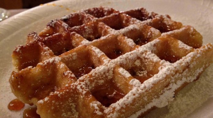 Waffle di zucca fatto senza burro e reso ancor più goloso dallo zucchero a velo e dallo sciroppo di acero d'accompagnamento Waffle di zucca senza burro servito conzucchero a velo e sciroppo di acero