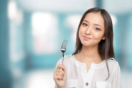 Giovane donna sorridente con forchetta in mano