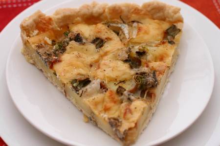 Fetta di quiche di patate, cipolle e gorgonzola nel piatto indiividuale 