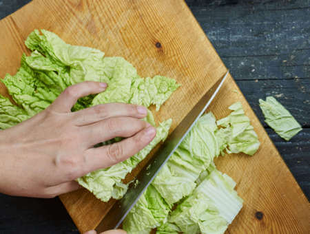 Foglie di verza tagliate a listarelle con il coltello sul tagliere