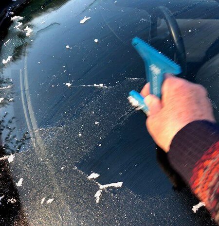 Uso corretto del raschietto per eliminare la brina dal vetro di una vettura