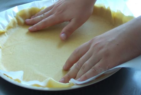 Pasta sfoglia cruda stesa manualmente nella teglia foderata con carta da forno