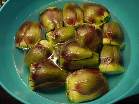 Ciotola contenente carciofi puliti a bagno in acqua acidulata