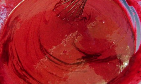 Ingredienti dell'impasto dei red velvet cupcakes mescolati con la frusta da cucina