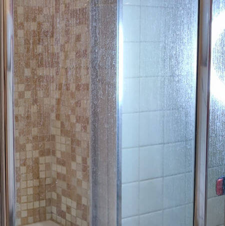 Vetro della doccia trasparente incrostato di calcare