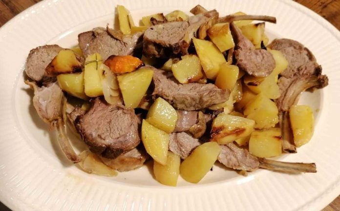 Invitanti costolette marinate e cotte nel forno con le patate Aspetto delle Costolette marinate e cucinate al forno assieme alle patate nel piatto di portata
