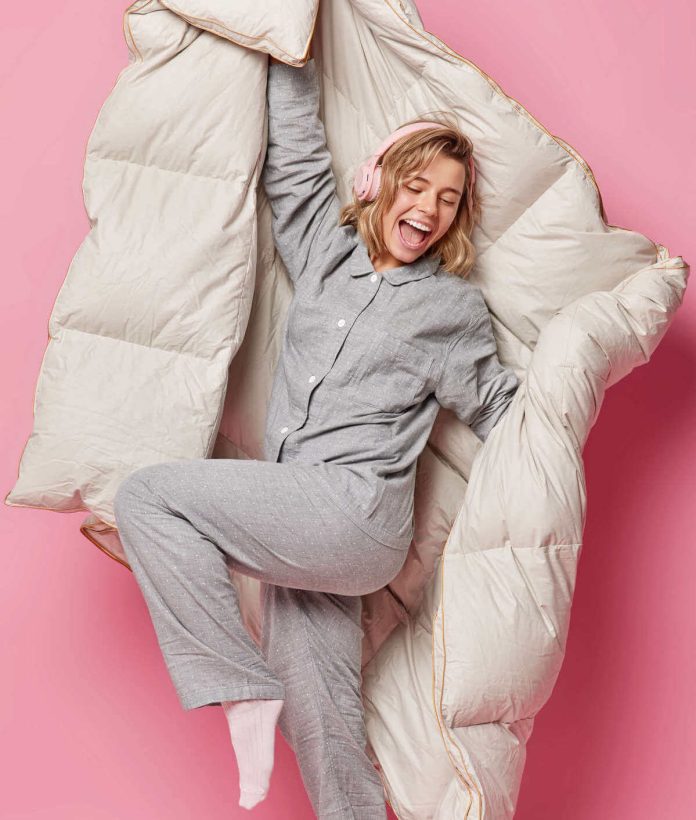 Giovane donna soddisfatta del piumone lavato e asciugato in casa a regola d'arte