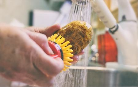 Come lavare le patate non pelate con lo spazzolino sotto l'acqua corrente 