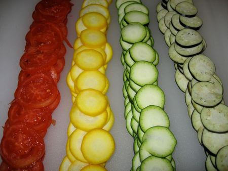 Zucchine verdi e gialle, pomodori e melanzane tagliate a fettine dello stesso spessore