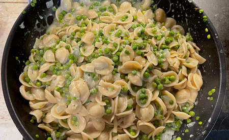 Orecchiette fatte saltare con piselli e cipolla nella padella