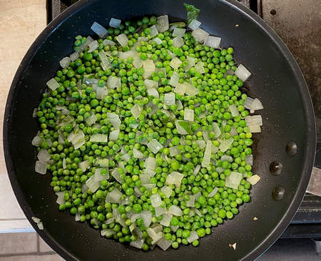 Piselli cuociono assieme alla cipolla tritata nella padella