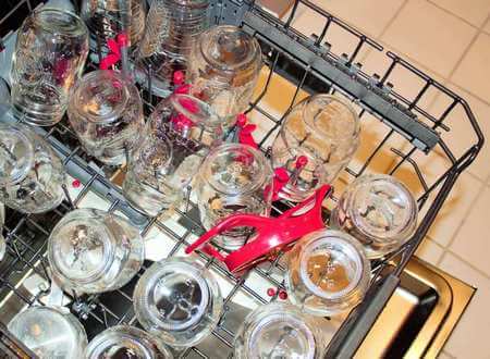 Vasetti per conserve di vetro sterilizzati a testa in giù nel cestello della lavastoviglie