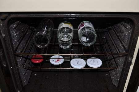 Vasetti di vetro vuoti e loro tappi sterilizzati nel forno