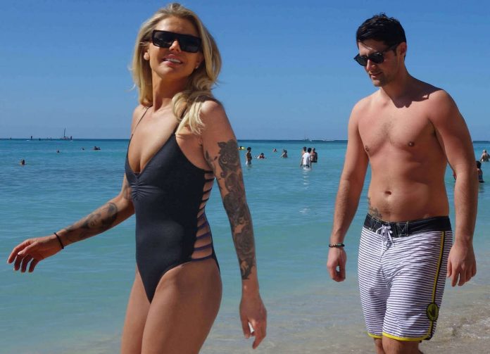 Donna e uomo con tatuaggi protetti con alto filtro solare sul bagnasciuga